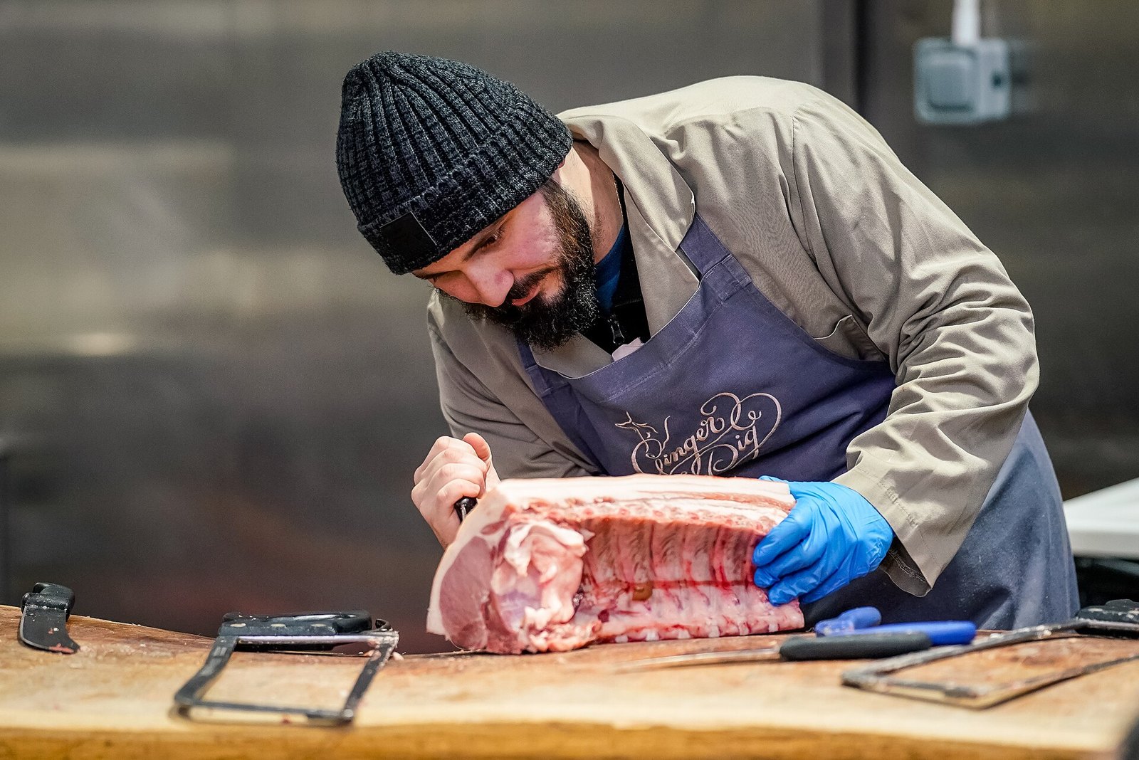 A butcher breaking down a side of beef by hand on a wooden block
